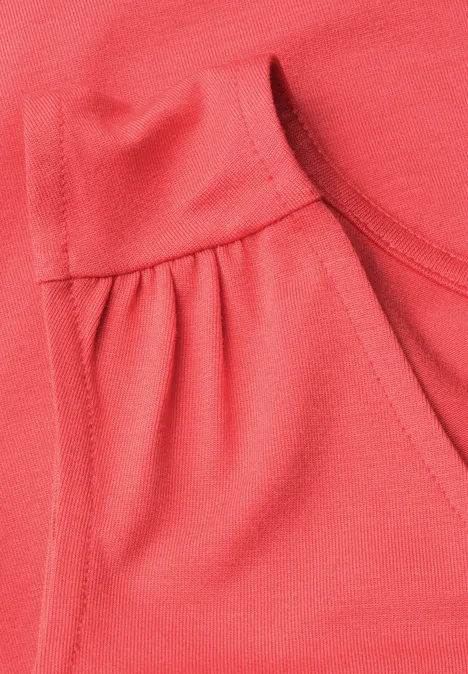 Top aus Jersey mit Elastiksaum sunset red Nahaufnahme eines korallfarbenen Shirts mit rundem Ausschnitt und seitlicher Raffung.