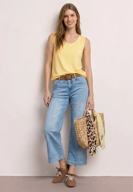 Top aus Jersey mit Elastiksaum soft yellow Frau mit gelbem Top, weitem Jeans-Culotte, braunem Gürtel und Korbtasche mit Leopardenmuster.