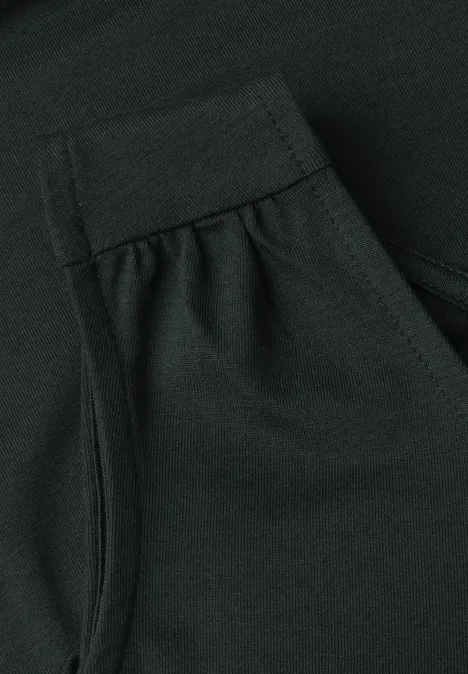 Gros plan d'un vêtement vert foncé en tissu avec couture apparente, pli et petite poche