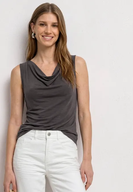 Top aspect soyeux avec décolleté cascade espresso brown Femme portant un haut sans manches gris à encolure drapée et un jean blanc, sur fond neutre.
