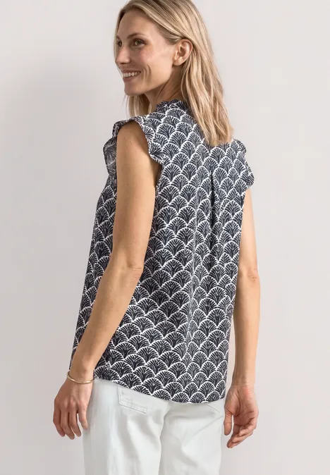 Top met verschillende texturen en gehaakte details shadowed navy Vrouw in mouwloze blouse met patroon en witte broek, zij-aanzicht tegen een lichte achtergrond.