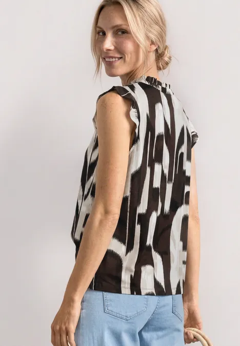 Femme de profil portant un top sans manches à motifs noir et blanc et un jean clair
