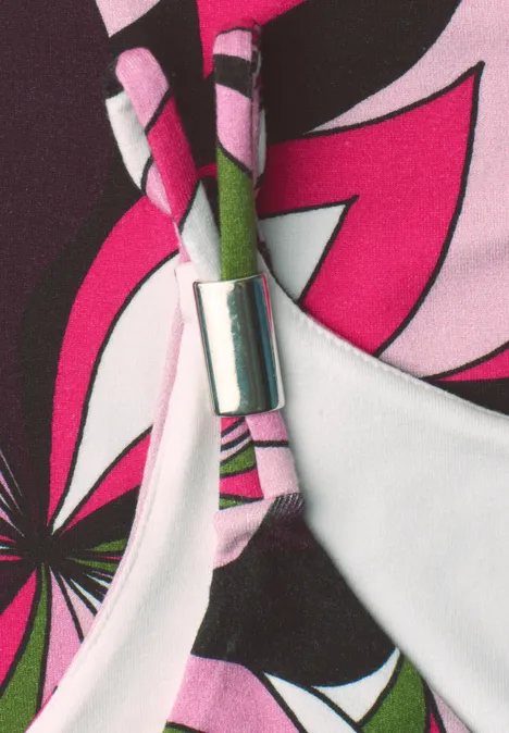 Detailaufnahme eines bunten Bikini-Oberteils mit pink-schwarzem Blumenmuster und silberner Klammer.