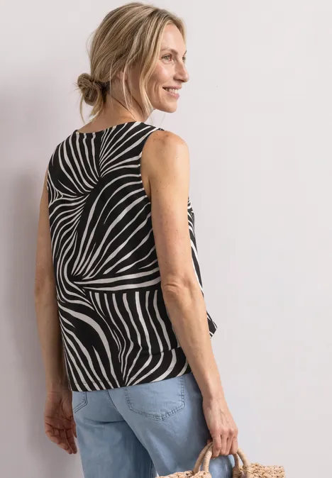 Frau von hinten in Zebra-Print-Top, blonder Dutt, Jeanshose und Strohtasche