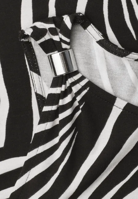 Nahaufnahme eines schwarz-weißen Zebra-Musters auf Stoff mit silbernem Metallverschluss.