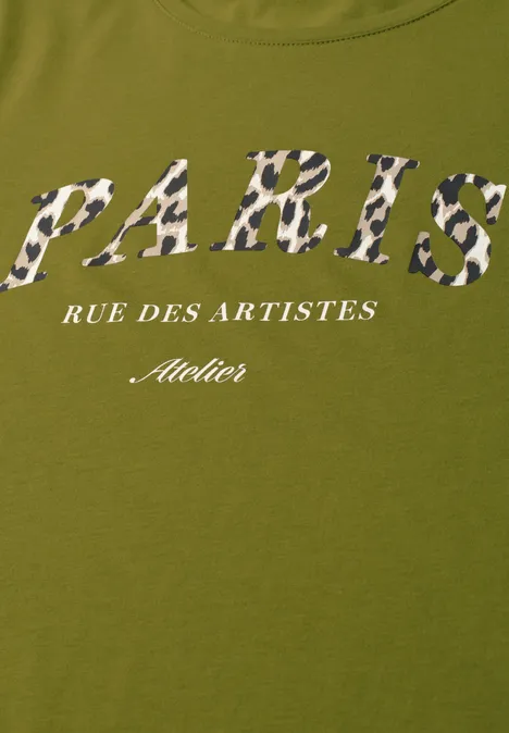 T-Shirt mit Wording Artwork shaded olive green Ein olivgrünes T-Shirt mit dem Schriftzug 'PARIS' in Camouflage-Muster, darunter 'RUE DES ARTISTES' und 'Atelier' in Weiß.