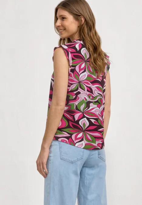 Top mit Strukturmix und Crochet-Details magenta dream Frau von hinten in buntem, ärmellosem Top mit pink-grünem Blumenmuster und hellblauen, weiten Jeans.