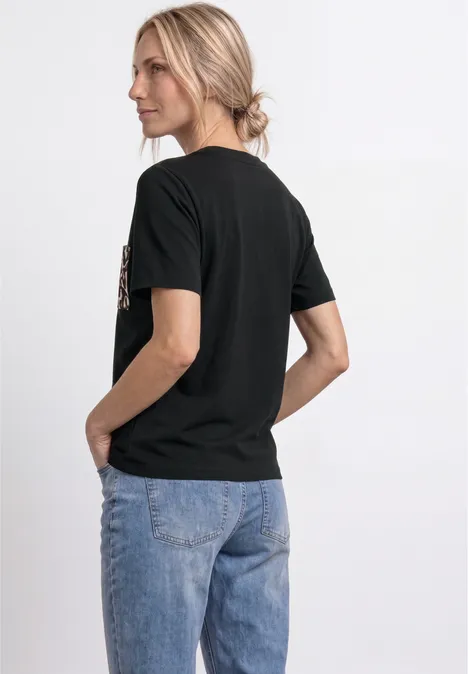 Dame von hinten in schwarzem T-Shirt und blauen Jeans.