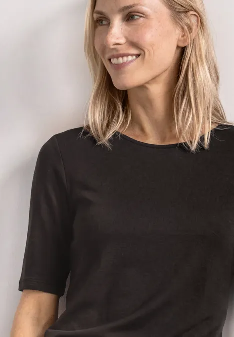 Basic Shirt met ronde hals in Unifarbe black coffee Vrouw met blond haar draagt een simpel zwart T-shirt met korte mouwen, vooraanzicht tot aan de borst.
