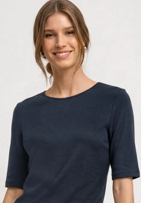 Vrouw met donkerblauw T-shirt, halflange mouwen en een ronde halslijn.