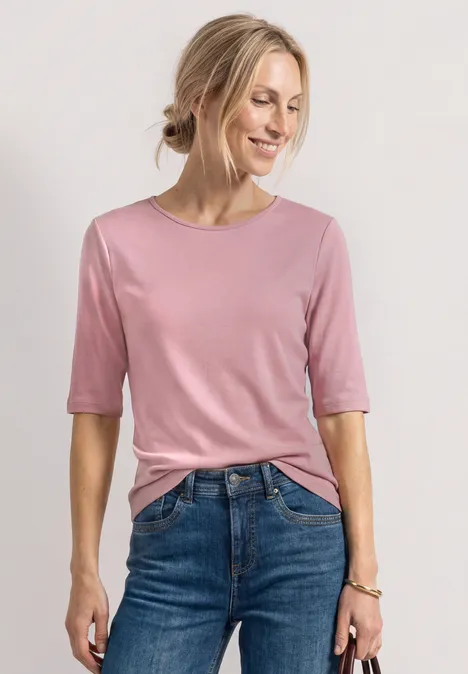 Vrouw in een roze T-shirt en blauwe spijkerbroek