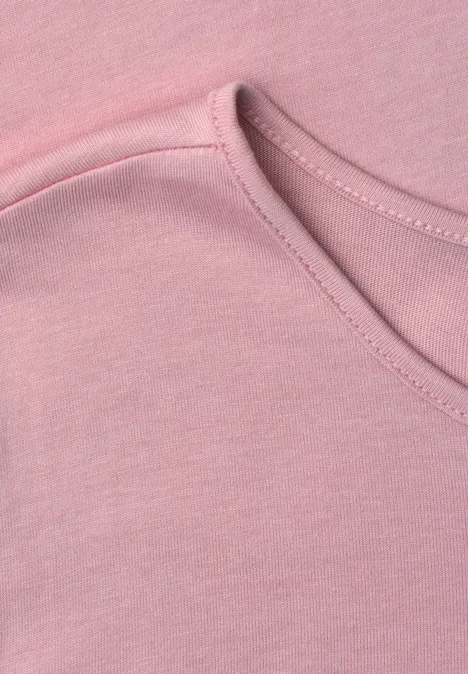 Close-up van een roze T-shirt met ronde halslijn.