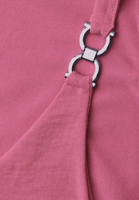 Nahaufnahme eines rosa Stoffes mit silberfarbenem Riemenring an einem Träger.