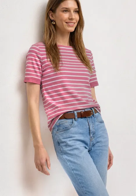 Frau in pink-weiß gestreiftem T-Shirt, hellblauen Jeans und braunem Gürtel, seitlich stehend.