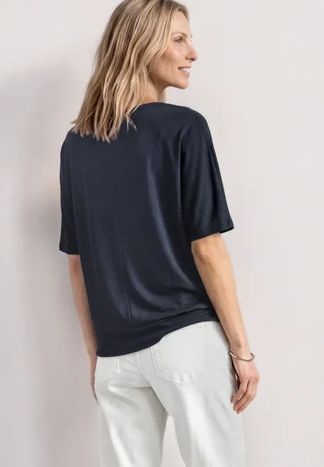 Basic Shirt met boothals en elastische zoom darkest blue Een persoon is van achteren te zien, draagt een donkerblauw T-shirt en een witte spijkerbroek.