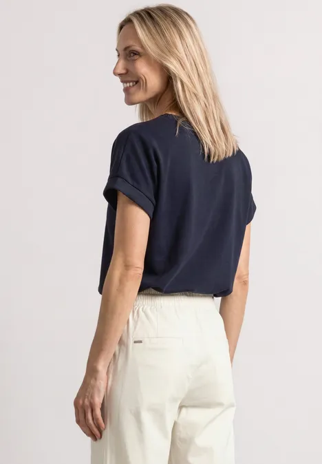 T-shirt avec un aspect soyeux à col rond darkest blue Vue latérale d'une femme portant un t-shirt bleu marine et un pantalon clair sur fond blanc