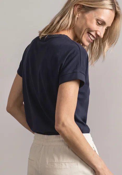 T-shirt avec un aspect soyeux à col rond darkest blue Une femme souriante vue de profil porte un t-shirt bleu foncé et un pantalon clair.