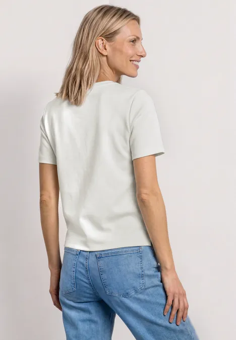 Vrouw van achteren met wit T-shirt en blauwe spijkerbroek voor neutrale achtergrond.