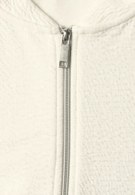 3/4-Arm Jacke mit Zipper und Struktur off white Nahaufnahme eines weißen, texturierten Jacke mit mittigem, silbernem Reißverschluss.