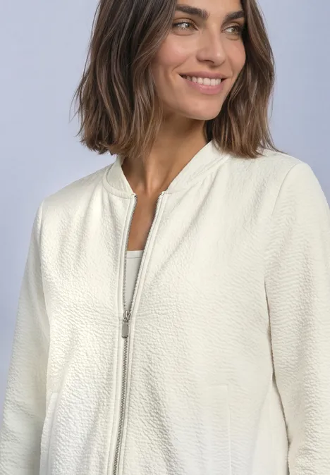3/4-Arm Jacke mit Zipper und Struktur off white Frau in cremefarbener, strukturierter Bomberjacke mit Reißverschluss und weißem Top, lächelt vor hellem Hintergrund.