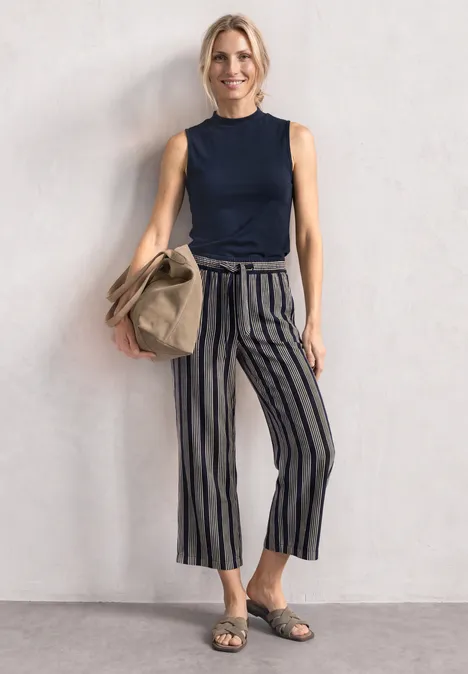 Top in Silk-Look met coltrui darkest blue Vrouw draagt marineblauw hemdje, gestreepte culotte, sandalen en houdt een beige tas.