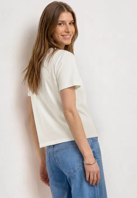 Frau von hinten in weißem T-Shirt und blauen Jeans, mit langen Haaren.