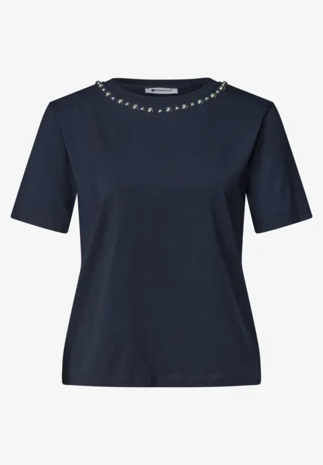 T-shirt bleu marine à manches courtes avec chaîne décorative en métal sur l'encolure ronde.