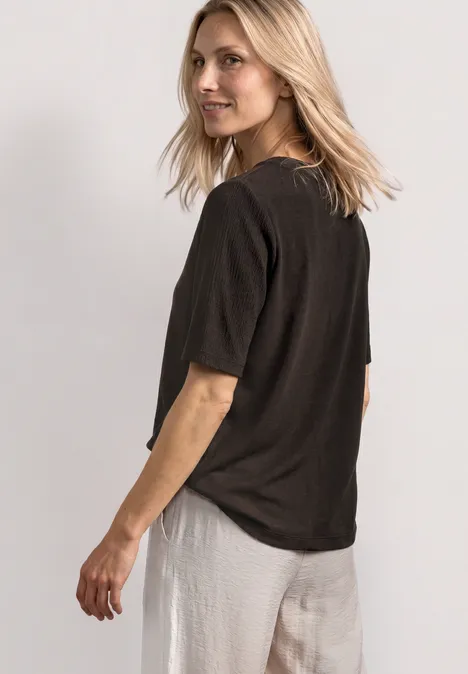 T-Shirt mit Rundhals und Knopfdeatils black coffee Seitlich abgebildete Frau mit blondem Haar, schwarzem T-Shirt und weißer Hose.