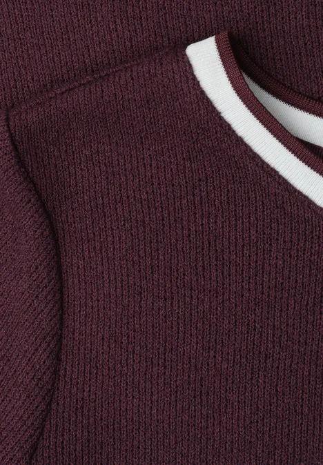 Close-up van een mouwloos bordeaux gebreid top met witte bies rond de ronde hals