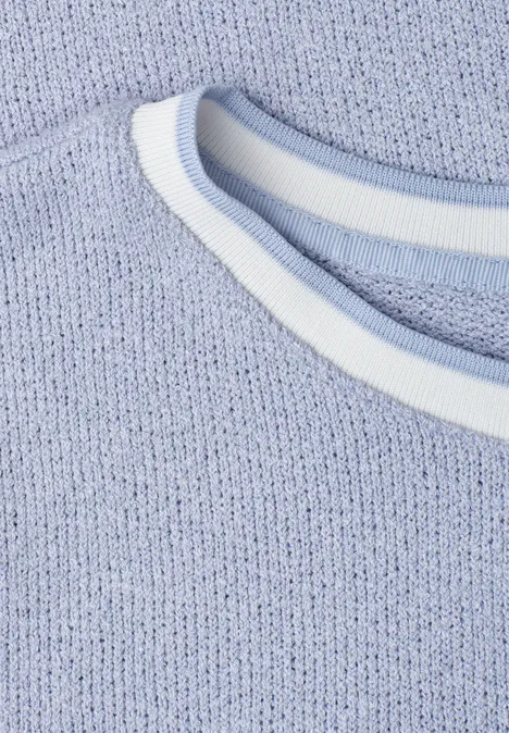 Close-up van een lichtblauw gebreid shirt met een witte, ronde halsafwerking.