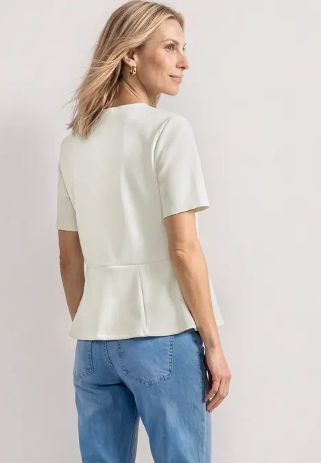 Shirt met ronde hals en volantdetail off white Witte getailleerde top met korte mouwen en peplum, gecombineerd met een blauwe spijkerbroek.
