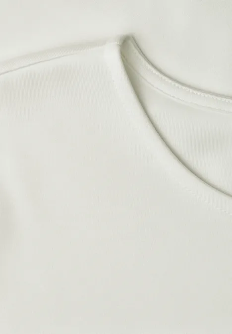 Shirt met ronde hals en volantdetail off white Close-up van een effen witte T-shirt halslijn.