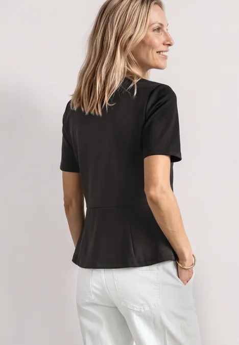 T-Shirt mit Rundhals und Volant-Detail black coffee Eine Frau steht von hinten in einem schwarzen T-Shirt mit kurzen Ärmeln und weißen Hosen vor hellem Hintergrund.