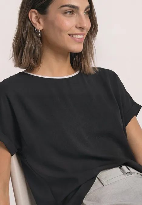 2-in-1 Shirt aus Chiffon mit Boat Neck Black Frau in schwarzer Bluse mit weißem Kragen und grauer Hose lächelnd gesehen