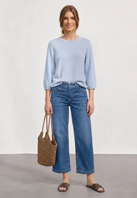 3/4-Arm Shirt mit Rundhals im Strick-Look whispery blue mel. Eine Frau trägt hellblauen Pullover, weite Cropped-Jeans, Basttasche und flache Sandalen vor neutralem Hintergrund.