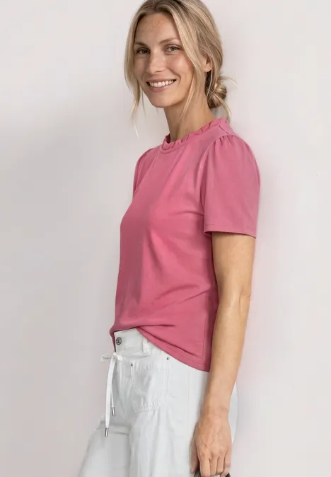 T-Shirt mit Rundhals und Rüschendetails blush berry Seitliches Profil einer Frau in pinkem T-Shirt und weißer Hose vor heller Wand.