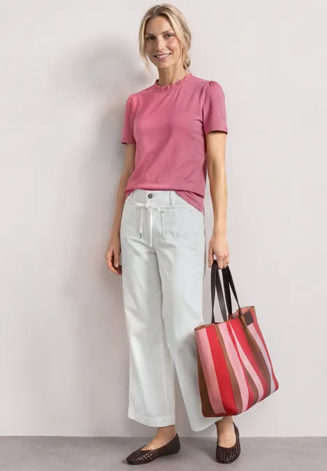 T-Shirt mit Rundhals und Rüschendetails blush berry Person trägt rosa T-Shirt, weiße weite Hose, braune Slipper und hält eine rot-gestreifte Tasche.
