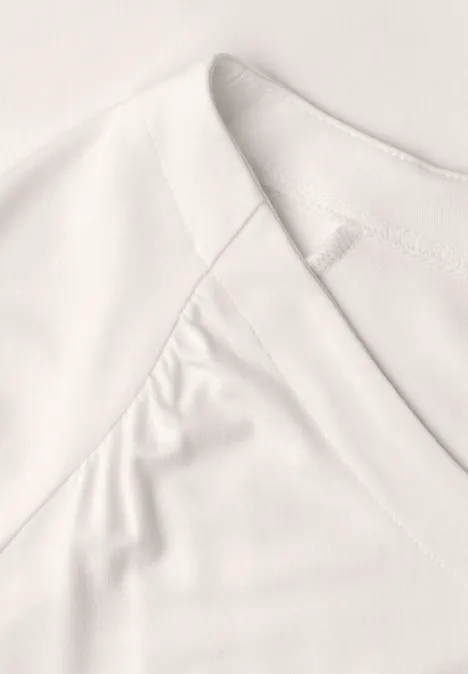 Nahaufnahme eines weißen V-Ausschnitt-Shirts mit feinem Stoff und sichtbaren Nähten.
