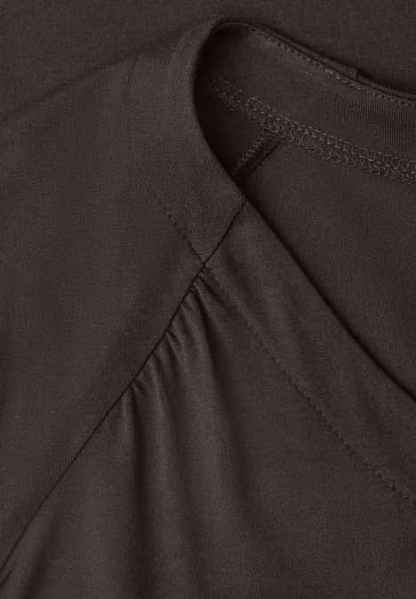 Close-up van een donker, glad textiel met zichtbare naad en lichte plooien.