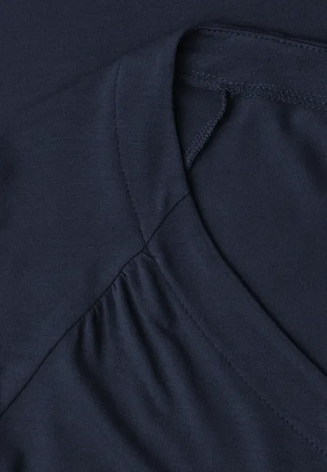 Gros plan sur un col de T-shirt bleu marine, coutures visibles et plis du tissu.