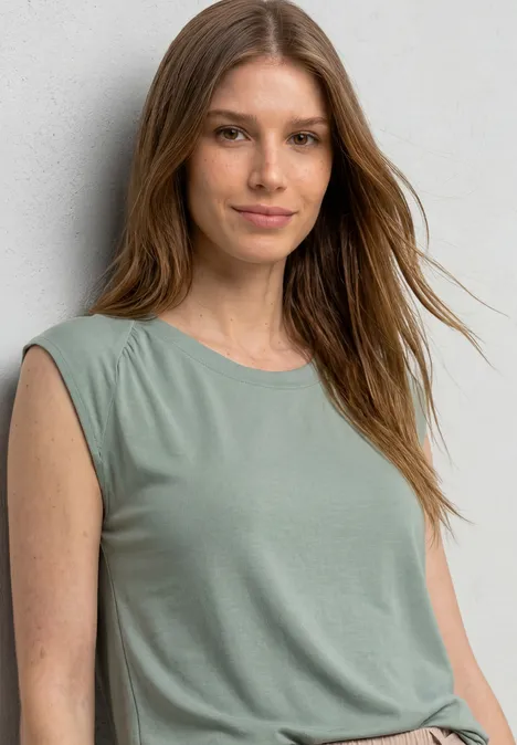 Dropped Shoulder Shirt mit Elastiksaum eucalyptus green Junge Frau mit langen braunen Haaren in ärmellosem hellgrünen Top vor grauer Wand.