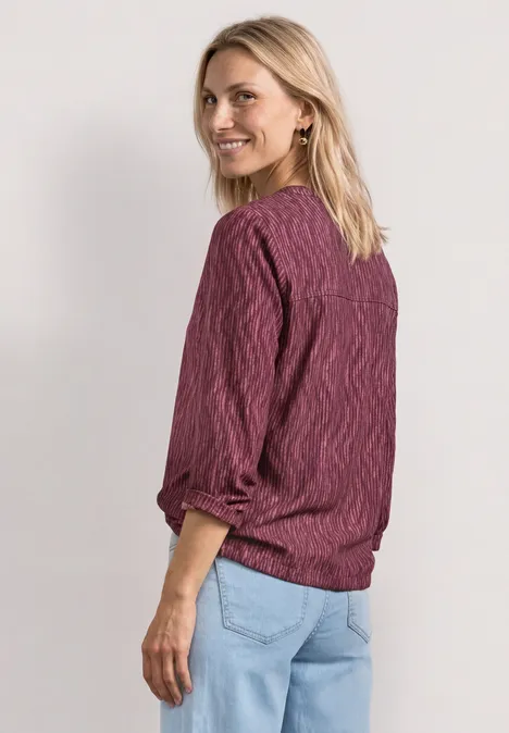 3/4-Arm Shirt mit Split Neck und Print blush berry Frau mit lila Pullover und Jeans, steht seitlich, Blick vom Betrachter weg