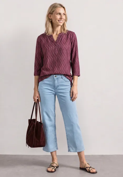 3/4-Arm Shirt mit Split Neck und Print blush berry Frau mit purpurroter Bluse, hellblauen Jeans, schwarzen Sandalen und brauner Tasche vor neutralem Hintergrund