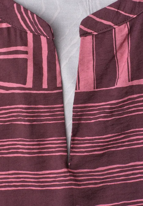 Gros plan sur un tissu bordeaux à rayures roses et encolure en V