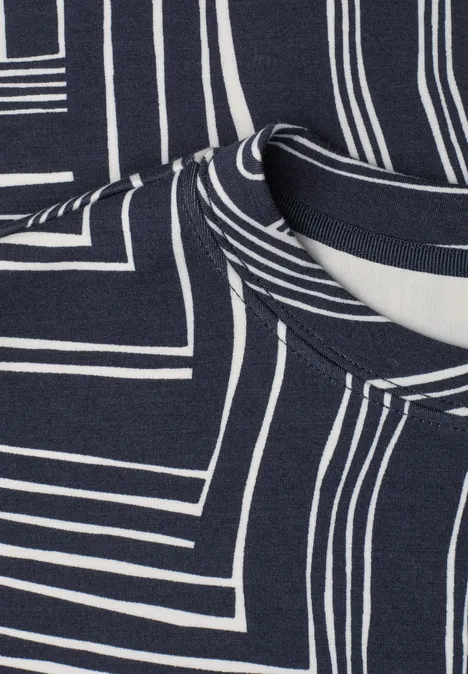 Close-up van donkerblauw stof met witte, geometrische lijnpatronen en zichtbare halslijn.