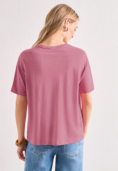 Vue de dos d'une femme portant un t-shirt ample rose et un jean bleu.