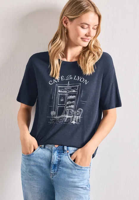 T-Shirt mit Rundhals und Frontprint darkest blue Frau trägt dunkelblaues T-Shirt mit Café-Motiv und steht lässig in Jeanshose, Hände in den Taschen.