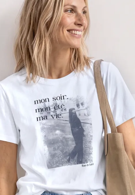 T-Shirt mit Rundhals und Fotoprint White Eine Person trägt ein weißes T-Shirt mit dem Aufdruck „mon soir. mon été. ma vie.“, Katzenmotiv und eine beige Tasche.