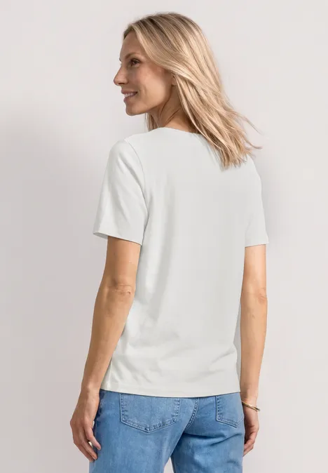 Basic T-Shirt mit Rundhals in Unifarbe off white Frau von hinten in weißem T-Shirt und blauen Jeans vor neutralem Hintergrund.