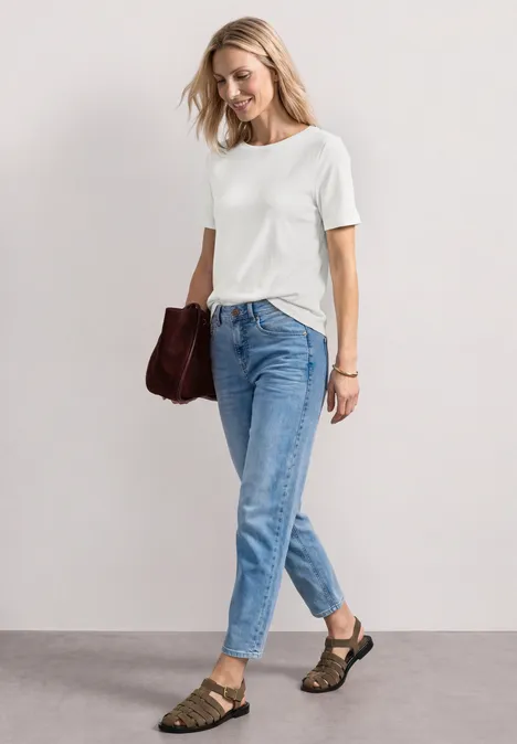 Basic T-Shirt mit Rundhals in Unifarbe off white Frau in weißem T-Shirt, blauen Jeans, braunen Sandalen und Tasche.